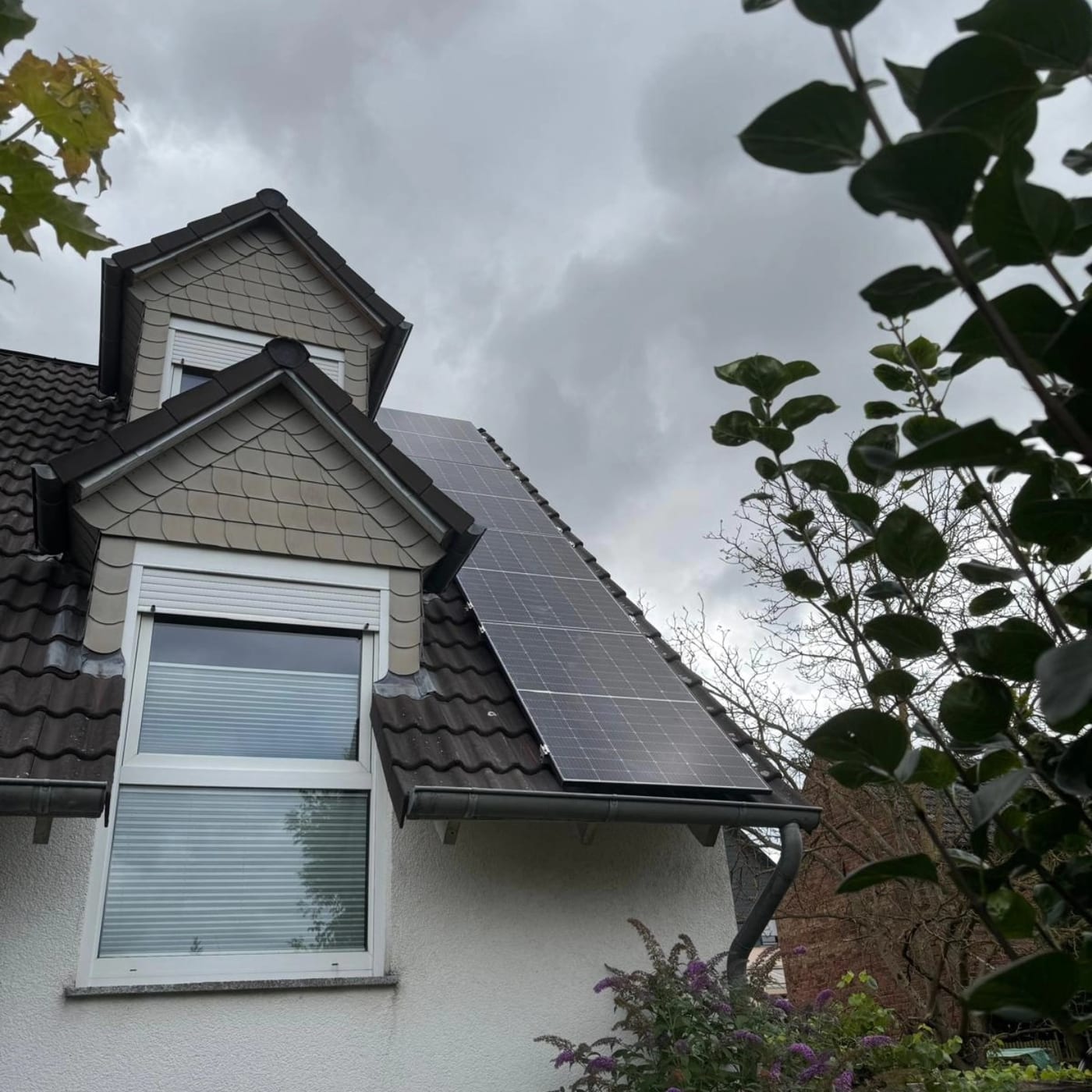 Photovoltaikmodule neben einer schiefergedeckten Gaube