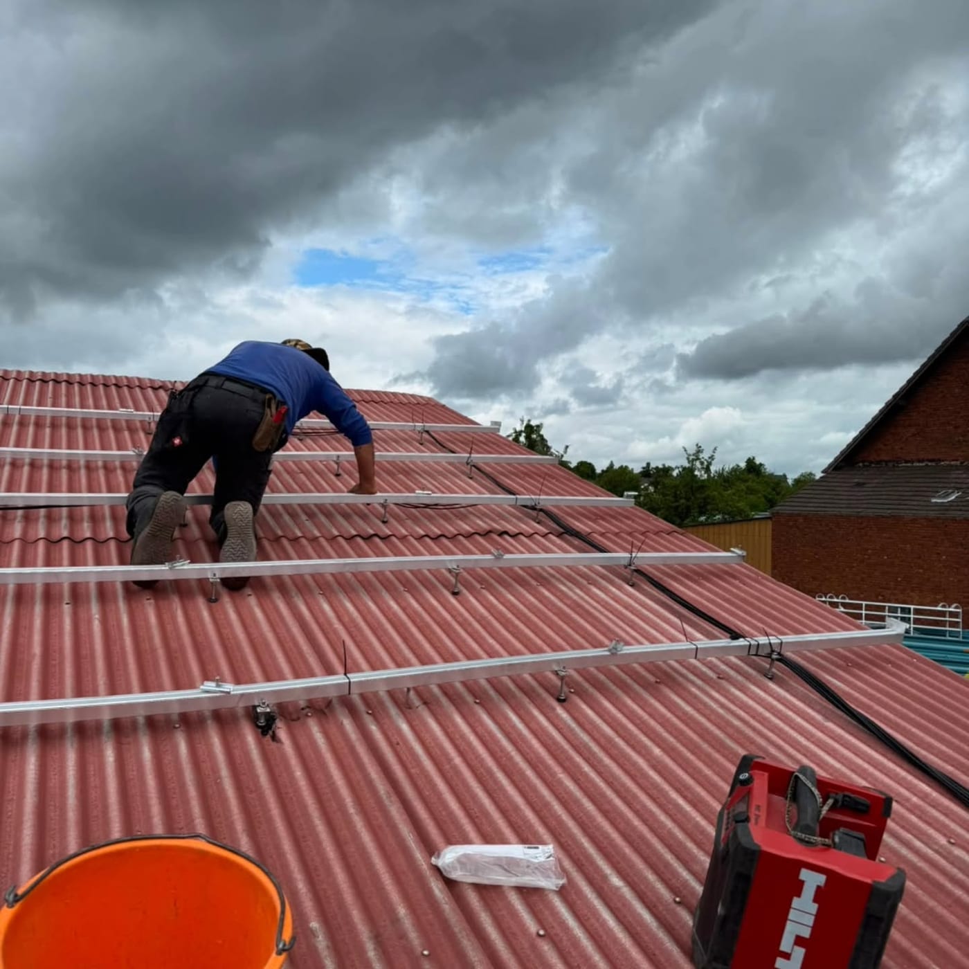 Montage der Photovoltaik-Unterkonstruktion auf einem roten Trapezblechdach
