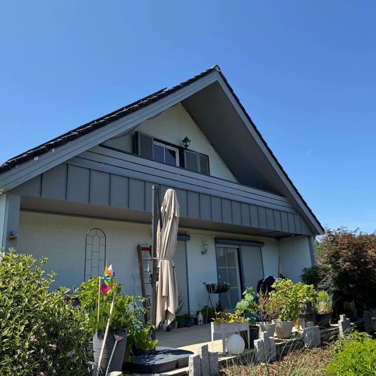 Wohnhaus mit stehfalzverkleidetem Giebel bei Sonnenschein